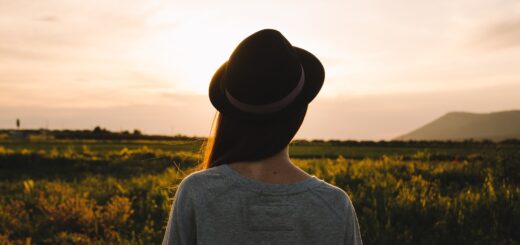 Mensch mit langem Haar und Hut vor Landschaft